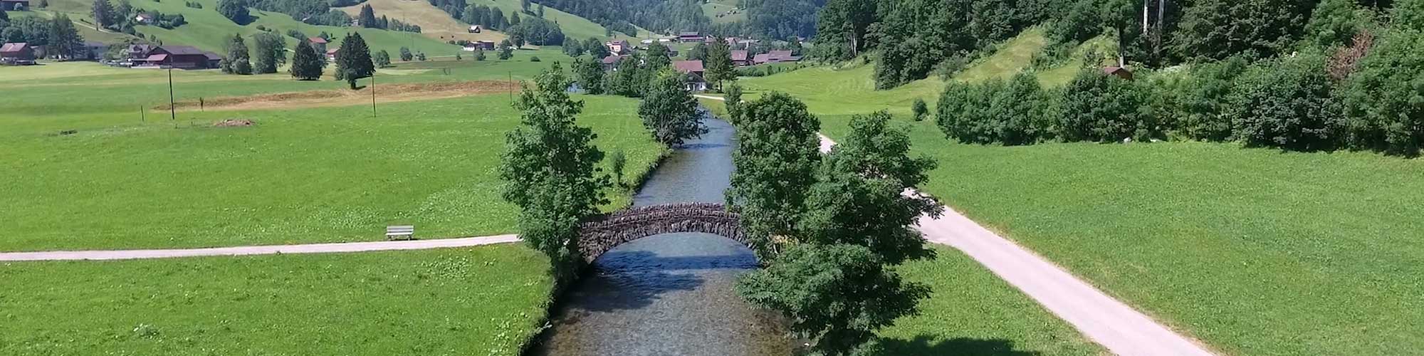 Flusslauf mit einer Steinbogenbrücke